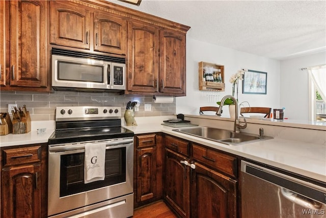kitchen with a sink, light countertops, decorative backsplash, and stainless steel appliances