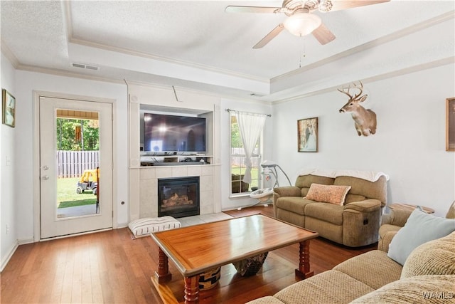 living area with visible vents, plenty of natural light, a raised ceiling, and crown molding