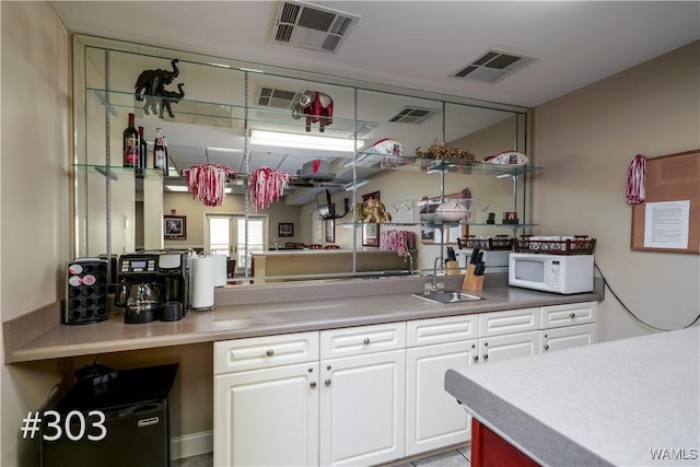 712 Frank Thomas Ave Unit 303, Tuscaloosa, AL 35401 - kitchen featuring a sink, white microwave, white cabinetry, and light countertops
