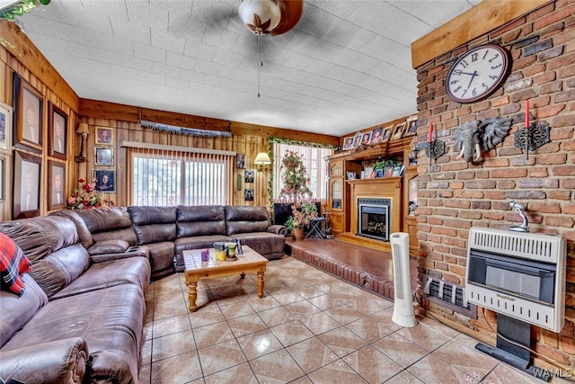 tiled living room featuring heating unit, wood walls, and a large fireplace