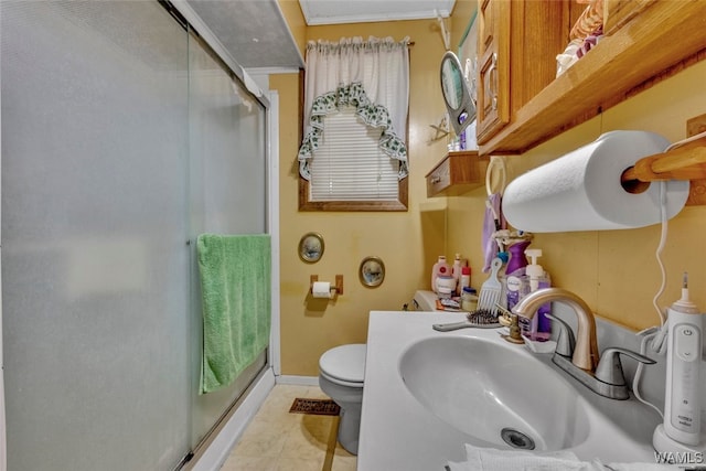 bathroom featuring sink, tile patterned floors, crown molding, an enclosed shower, and toilet