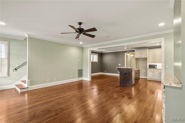 unfurnished living room with ceiling fan, sink, dark hardwood / wood-style floors, and ornamental molding