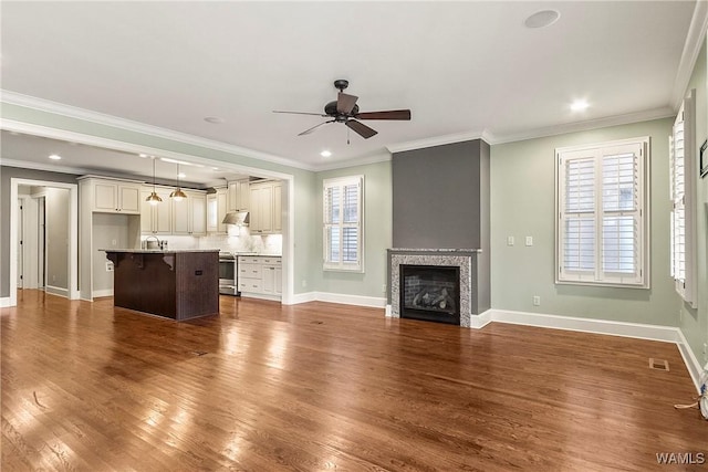 unfurnished living room with ceiling fan, sink, ornamental molding, and dark wood-type flooring