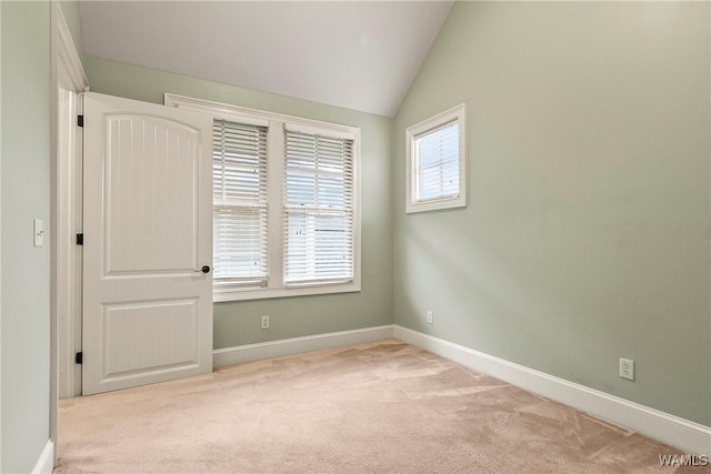 carpeted empty room featuring lofted ceiling