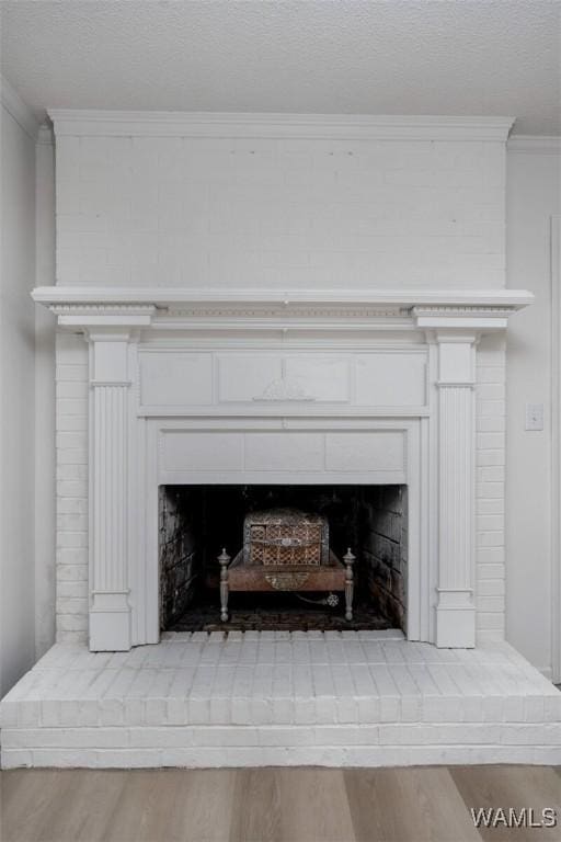 4205 Cloverdale Est, Northport, AL 35473 - detailed view of a fireplace with raised hearth, ornamental molding, wood finished floors, and a textured ceiling