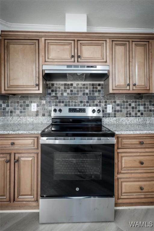 4205 Cloverdale Est, Northport, AL 35473 - kitchen with stainless steel range with electric cooktop, under cabinet range hood, tasteful backsplash, and brown cabinetry