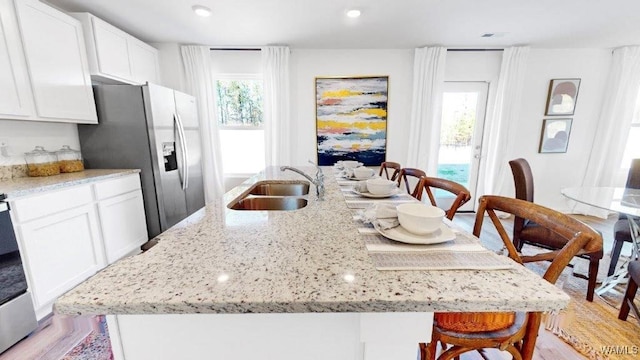 kitchen with a wealth of natural light, sink, stainless steel refrigerator with ice dispenser, and light hardwood / wood-style flooring