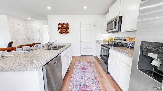 kitchen with white cabinetry, sink, light hardwood / wood-style floors, and appliances with stainless steel finishes