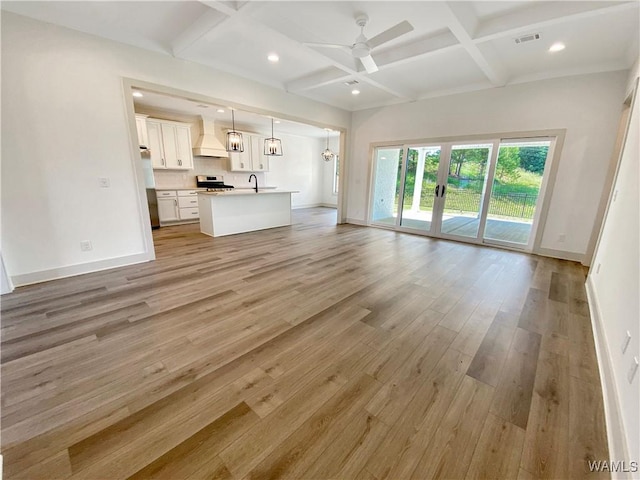 unfurnished living room with beam ceiling, light hardwood / wood-style floors, ceiling fan, and coffered ceiling