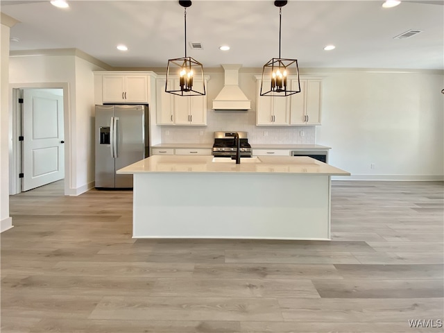 kitchen with decorative light fixtures, custom range hood, stainless steel appliances, and light hardwood / wood-style flooring