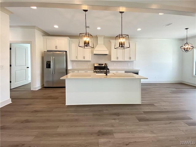 kitchen with appliances with stainless steel finishes, custom exhaust hood, pendant lighting, a center island with sink, and white cabinetry