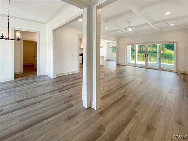 unfurnished living room with ceiling fan with notable chandelier, light hardwood / wood-style flooring, beamed ceiling, and coffered ceiling