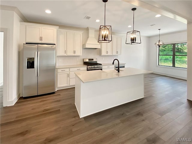 kitchen with appliances with stainless steel finishes, premium range hood, hanging light fixtures, and a center island with sink