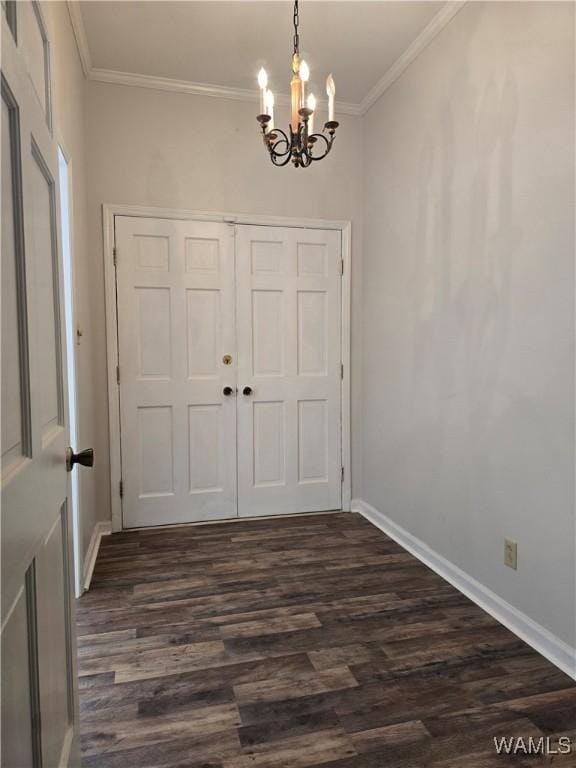 entryway with crown molding, dark wood-type flooring, and a notable chandelier