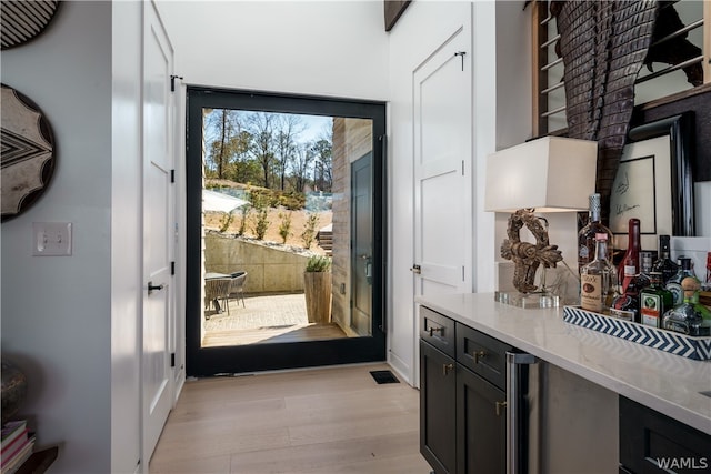 doorway to outside with light hardwood / wood-style floors and indoor bar