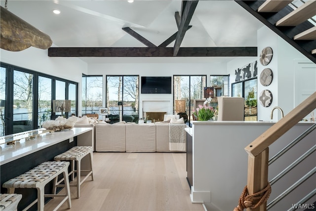 kitchen with beamed ceiling, a healthy amount of sunlight, and light wood-type flooring