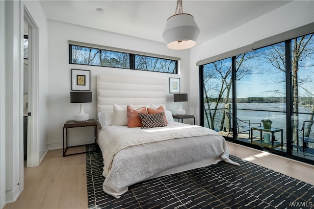 bedroom featuring hardwood / wood-style floors and a water view