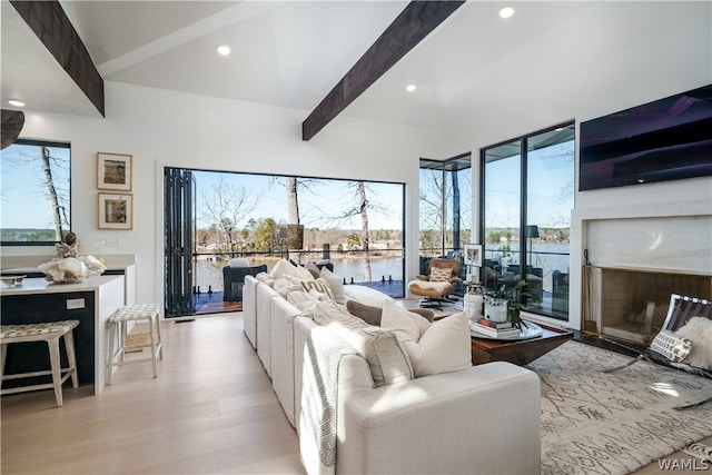 living room featuring beam ceiling, light hardwood / wood-style floors, and a wealth of natural light