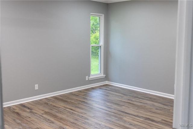 empty room with baseboards, plenty of natural light, ornamental molding, and dark wood-type flooring