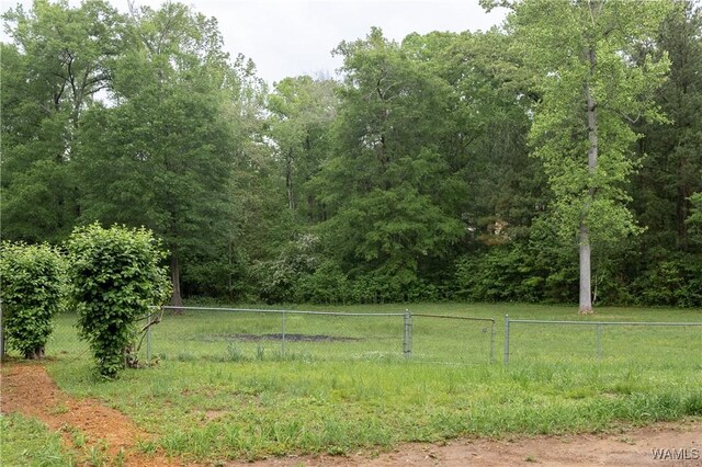 view of yard featuring fence and a wooded view