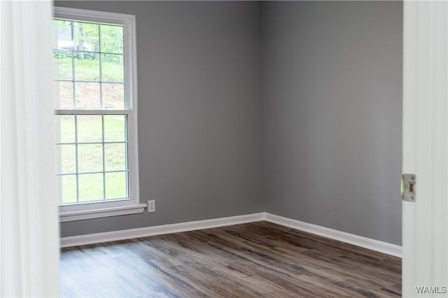 unfurnished room with baseboards and dark wood-type flooring