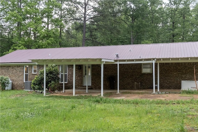 ranch-style home featuring central air condition unit, brick siding, and metal roof