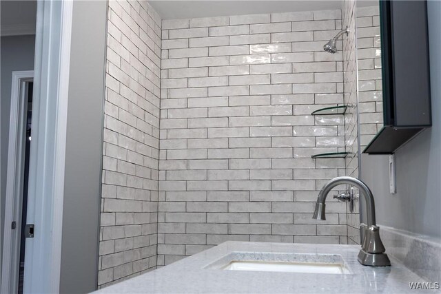 bathroom with tiled shower and a sink