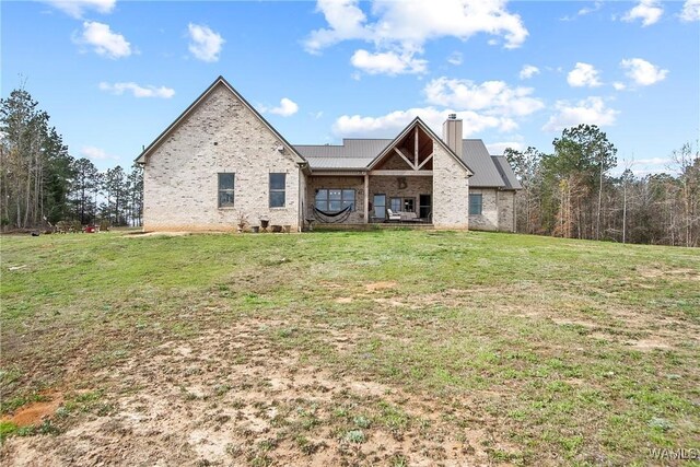 17505 Mormon Rd, Northport, AL 35475 - back of house featuring a chimney, a lawn, metal roof, and brick siding