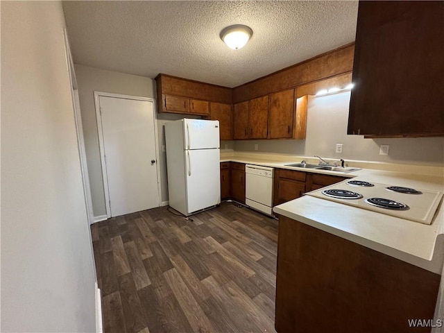 kitchen with dark wood-type flooring, white appliances, sink, and a textured ceiling