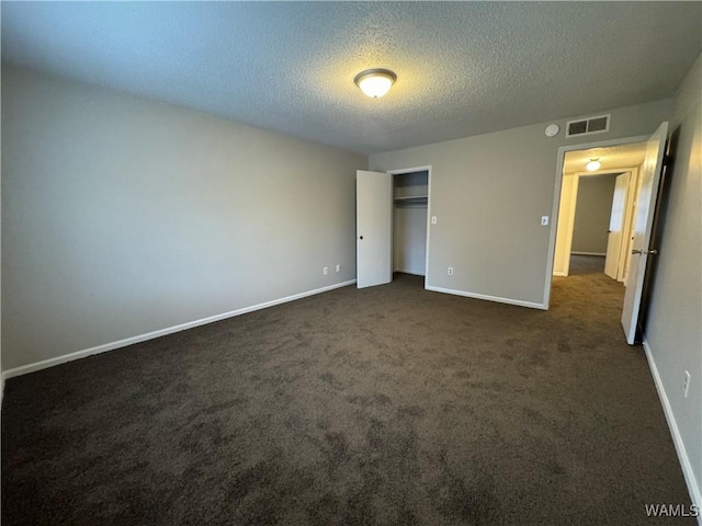 unfurnished bedroom with dark colored carpet, a textured ceiling, and a closet