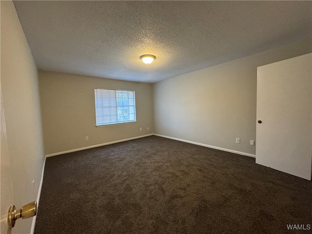 empty room featuring a textured ceiling and dark carpet