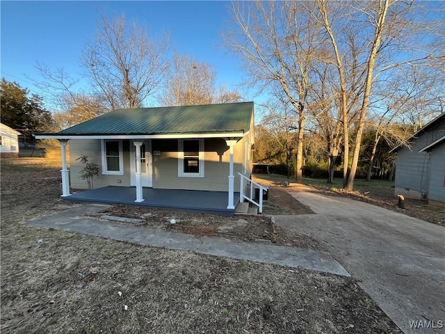 view of front of house featuring covered porch, metal roof, and driveway