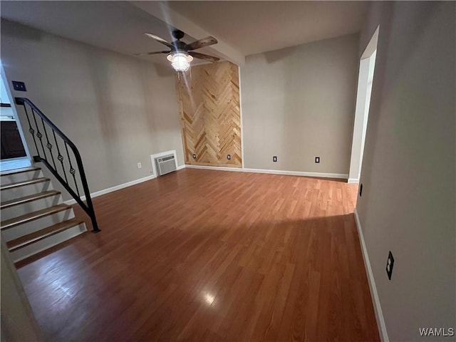 unfurnished living room with stairway, wood finished floors, and baseboards