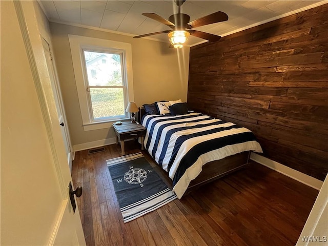 bedroom featuring baseboards, dark wood-type flooring, visible vents, and wooden walls