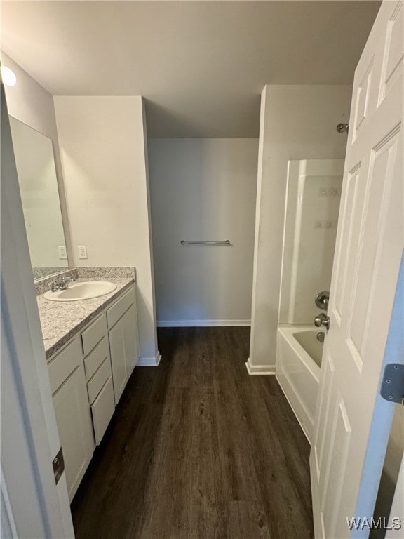bathroom featuring baseboards,  shower combination, wood finished floors, and vanity