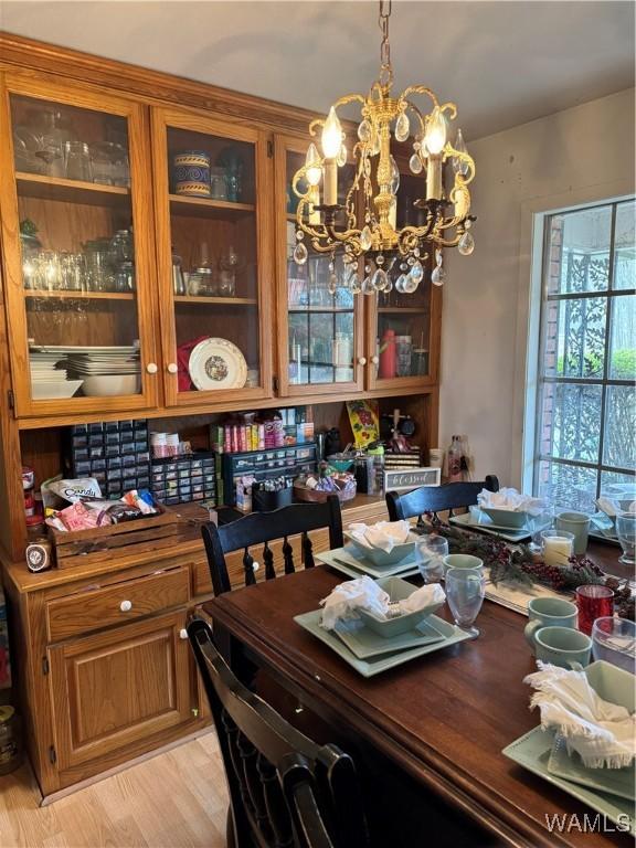 dining space with light hardwood / wood-style floors and an inviting chandelier