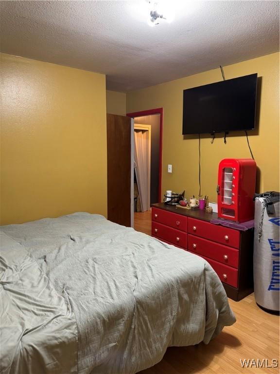 bedroom featuring a textured ceiling and light hardwood / wood-style floors