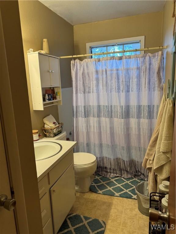 bathroom featuring a shower with curtain, tile patterned flooring, vanity, and toilet