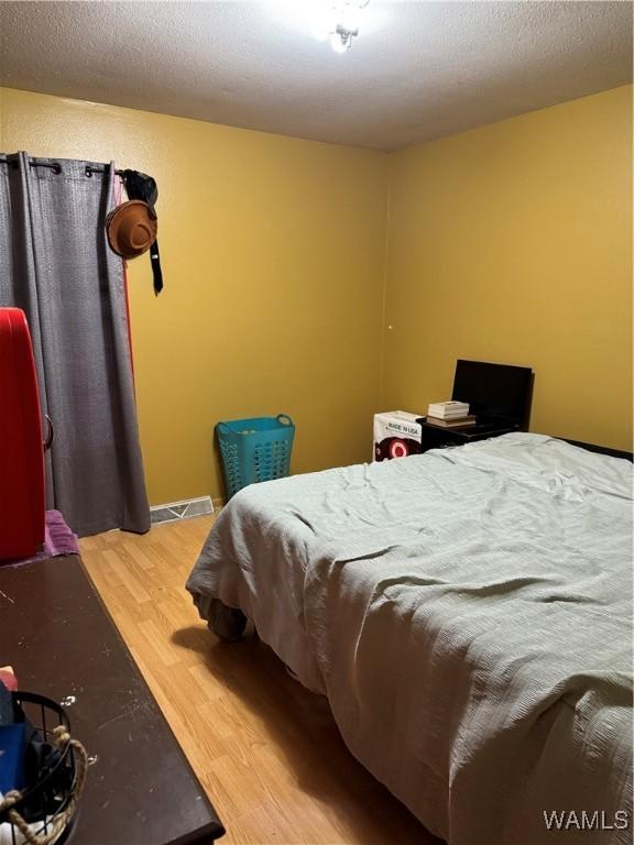 bedroom featuring a textured ceiling and hardwood / wood-style flooring