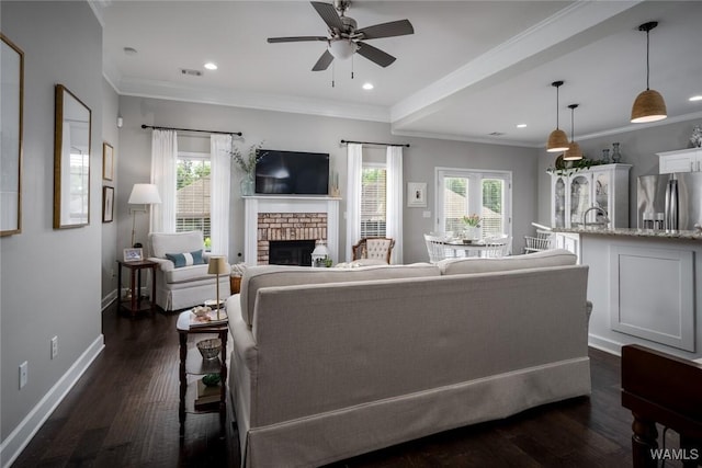 living room with a brick fireplace, ceiling fan, baseboards, and a healthy amount of sunlight