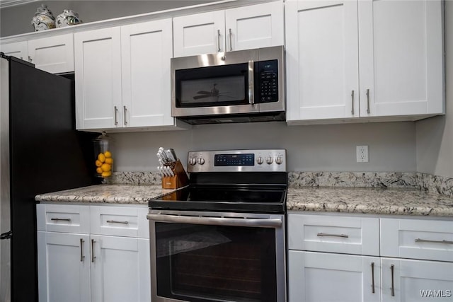 kitchen featuring light stone countertops, stainless steel appliances, and white cabinetry