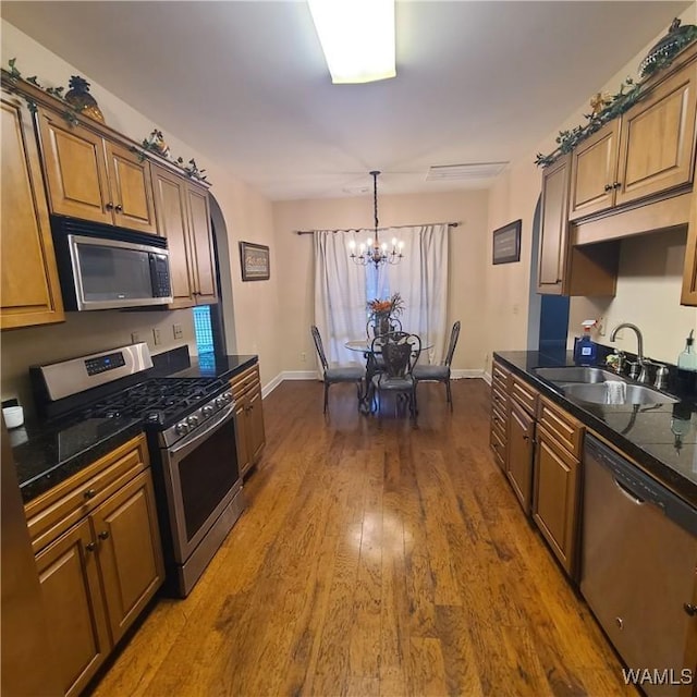 13712 Tab Dr, Northport, AL 35475 - kitchen featuring stainless steel appliances, a sink, dark countertops, baseboards, and a chandelier