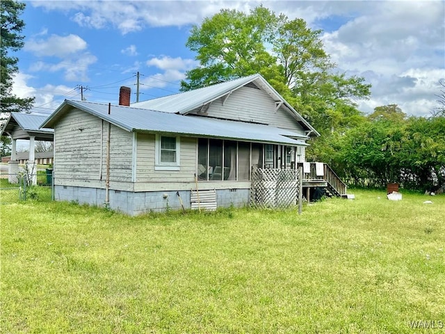 rear view of property featuring a sunroom, a yard, metal roof, crawl space, and a chimney