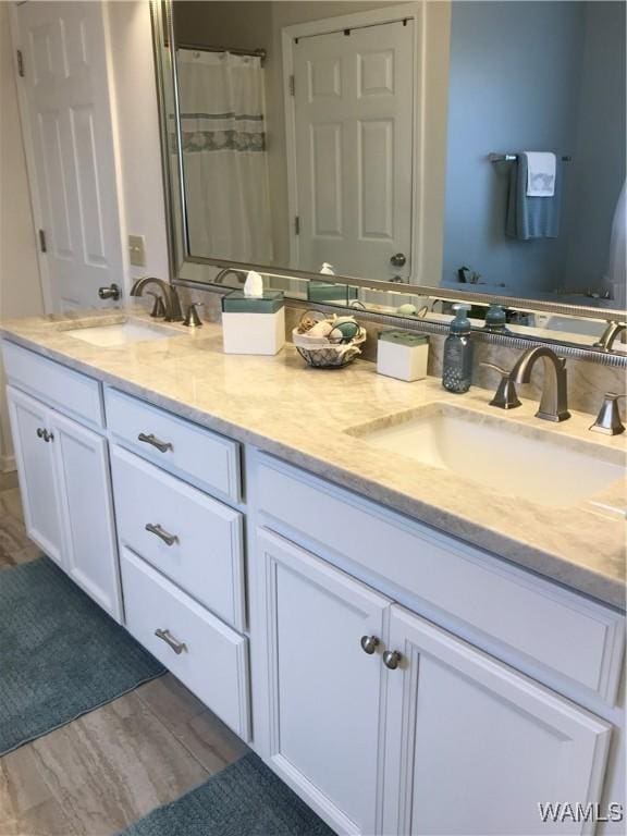 bathroom with double vanity, a sink, and wood finished floors