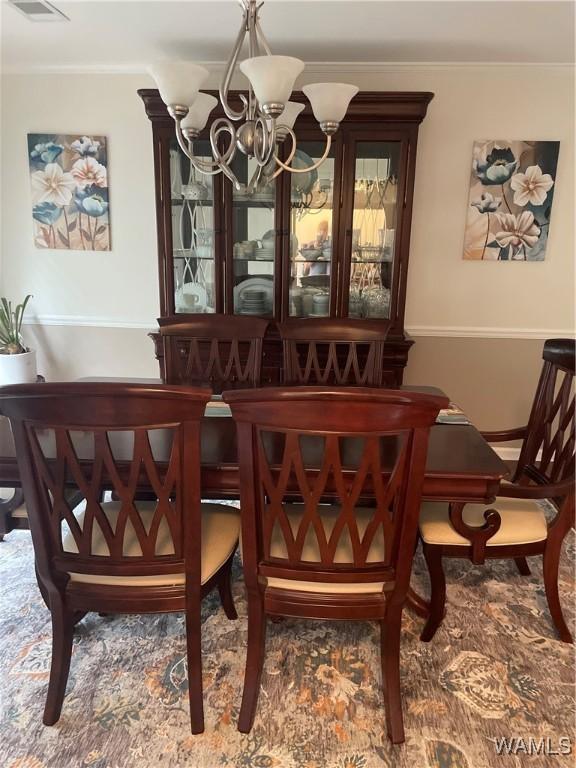 dining space featuring an inviting chandelier, visible vents, and crown molding