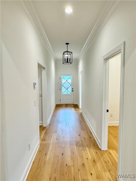 entryway featuring ornamental molding, a chandelier, and light wood-type flooring