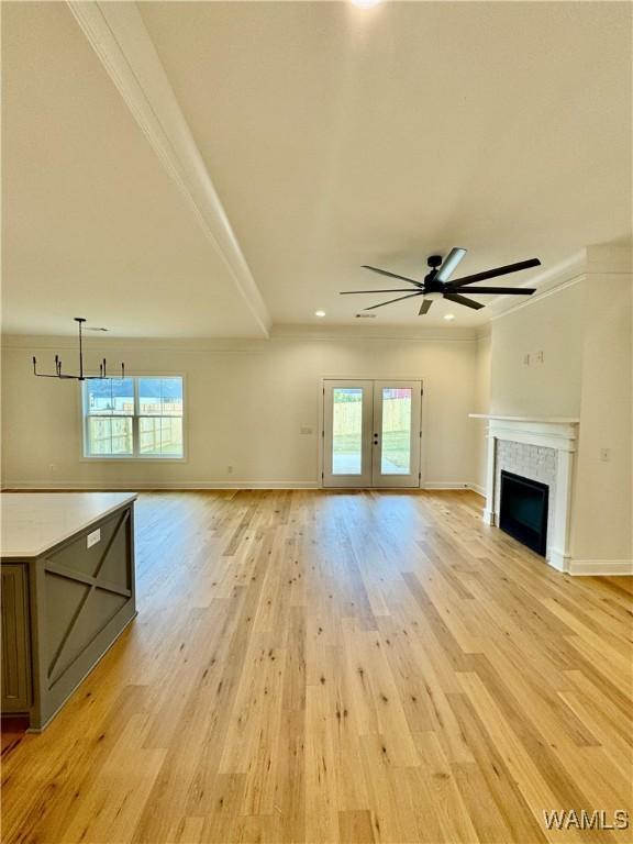 unfurnished living room featuring crown molding, a healthy amount of sunlight, a tile fireplace, and light hardwood / wood-style flooring