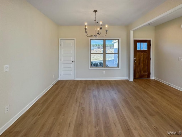 unfurnished dining area with an inviting chandelier and hardwood / wood-style floors