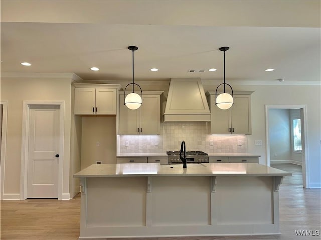 kitchen with a kitchen island with sink, pendant lighting, and custom range hood