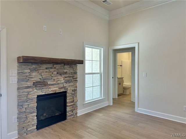 unfurnished living room with light hardwood / wood-style floors, crown molding, and a fireplace